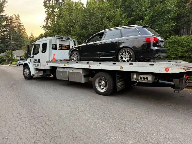 Zee's Towing loading a luxury sedan at dusk in Happy Valley, Oregon